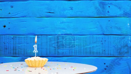 Téléchargez les photos : Fond festif avec un gâteau sur le fond de planches bleues, espace de copie, un beau fond pour un anniversaire avec un chiffre une bougie avec une figure 1 - en image libre de droit