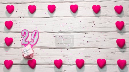 Foto de Tarjeta de cumpleaños feliz para una chica en tonos rosados, vista superior, espacio para copiar. Hermosas felicitaciones con números y corazones, un lugar para su texto. feliz cumpleaños vela número 29 - Imagen libre de derechos