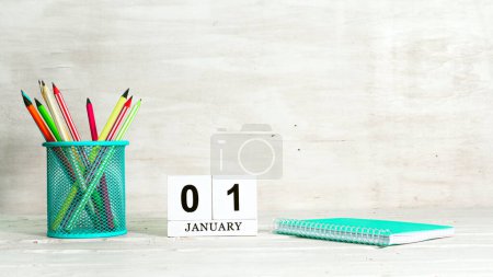 January 1 calendar. The concept of the date of the season. Pencils in a basket against the background of a notebook and the date of the month. Copy space calendar cube