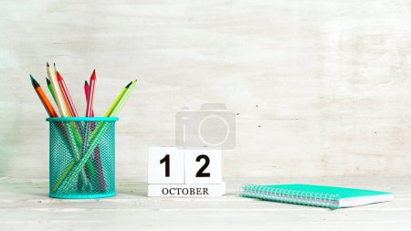 Foto de Calendario del 12 de octubre. El concepto de la fecha de la temporada. Lápices en una canasta sobre el fondo de un cuaderno y la fecha del mes. Copia espacio cubo de calendario - Imagen libre de derechos