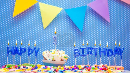 Foto de A word made from the letters of happy birthday candles for a one year old child. Copy space Happy birthday greetings for 1 year old, lit candles with holiday decorations. Beautiful holiday card - Imagen libre de derechos