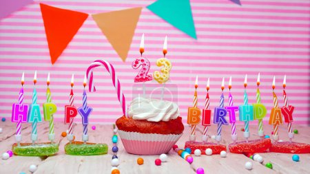Téléchargez les photos : Happy birthday card on a pink background, with a number in a cupcake. Beautiful happy birthday background with number 23 with burning candle. Festive background with colorful decorations - en image libre de droit