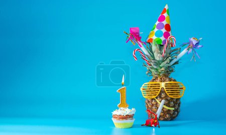 Foto de Creative congratulations on one year old for a newborn baby. Pineapple with glasses in festive decorations. copy space. 1 year old birthday. - Imagen libre de derechos