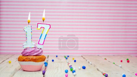 Foto de Muffin with cream and number 17 for a birthday on a pink background, copy space, holiday background. Happy birthday greetings for seventeen years old - Imagen libre de derechos