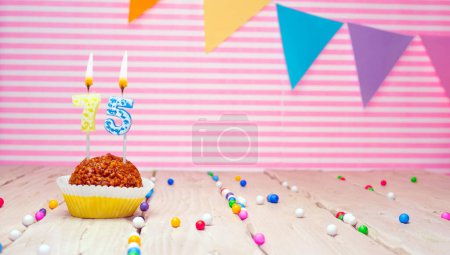 Happy birthday to 75 years old. Festive background with muffin. Copy space birthday card for seventy-five years on a pink background.