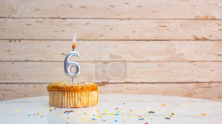 Téléchargez les photos : Happy birthday greetings for 6 years from silver numbers on the background of white boards copy space. Beautiful birthday card with a muffin with a burning candle for six years - en image libre de droit