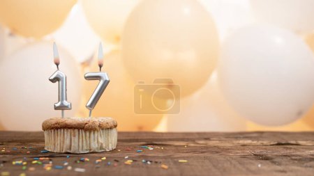 Téléchargez les photos : Happy birthday card with candle number 17 in a cupcake against the background of balloons. Copy space happy birthday for 16 years old. - en image libre de droit