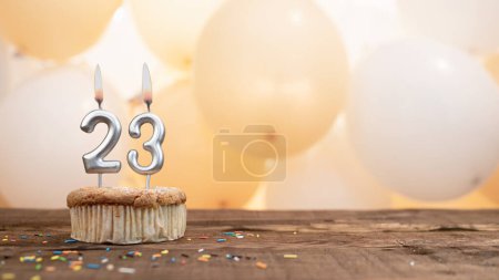 Téléchargez les photos : Happy birthday card with candle number 23 in a cupcake against the background of balloons. Copy space happy birthday for twenty three years old. - en image libre de droit