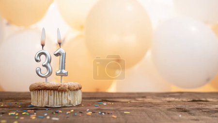 Happy birthday card with candle number 31 in a cupcake against the background of balloons. Copy space happy birthday for thirty one year old