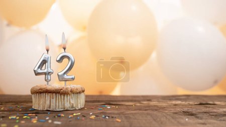 Téléchargez les photos : Happy birthday card with candle number 42 in a cupcake against the background of balloons. Copy space happy birthday for forty one years old. - en image libre de droit