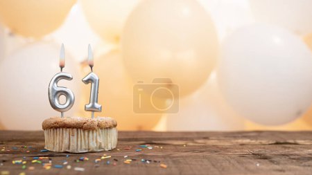 Happy birthday card with candle number 61 in a cupcake against the background of balloons. Copy space happy birthday for sixty one summer