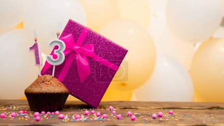Photo for Happy birthday with a pink gift box for a 13 year old girl. Beautiful birthday card with a cupcake and a burning candle number thirteen - Royalty Free Image