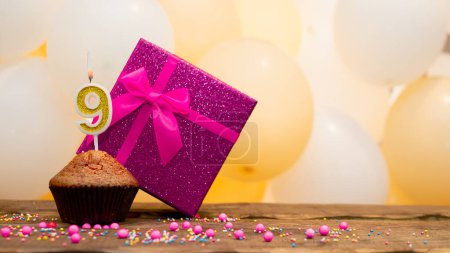 Téléchargez les photos : Happy birthday with pink gift box for 9 year old girl. Beautiful birthday card with cupcake and number nine burning candle - en image libre de droit