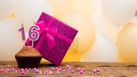 Foto de Happy birthday with a pink gift box for a 16 year old girl. Beautiful birthday card with a cupcake and a burning candle number sixteen - Imagen libre de derechos