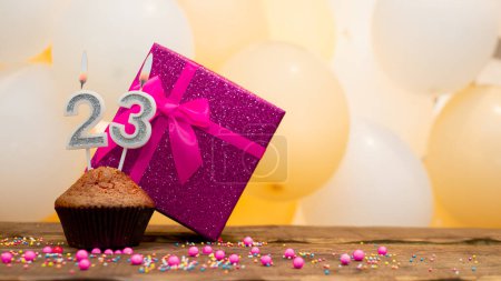 Téléchargez les photos : Happy birthday with a pink gift box for a 23 year old girl. Beautiful birthday card with a cupcake and a burning candle number twenty three - en image libre de droit