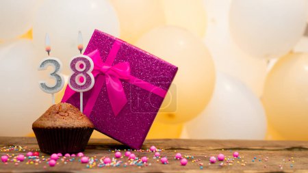 Téléchargez les photos : Happy birthday with a pink gift box for a 38 year old girl. Beautiful birthday card with cupcake and burning candle number thirty eight. - en image libre de droit