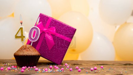 Happy birthday with pink gift box for 40 year old woman. Beautiful birthday card with cupcake and number forty burning candle