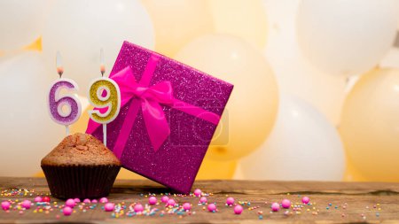 Foto de Happy birthday with a pink gift box for a 69 year old woman. Beautiful birthday card with cupcake and burning candle number sixty nine - Imagen libre de derechos