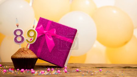 Téléchargez les photos : Happy birthday with pink gift box for 89 year old woman. Beautiful birthday card with cupcake and burning candle number eighty nine - en image libre de droit