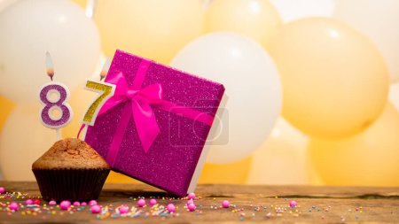 Téléchargez les photos : Happy birthday with pink gift box for 87 year old woman. Beautiful birthday card with a cupcake and a burning candle number eighty seven - en image libre de droit