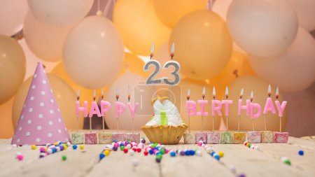 Téléchargez les photos : Beautiful background happy birthday number 23 with burning candles, birthday candles pink letters for twenty three years. Festive background with balloons - en image libre de droit