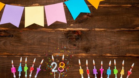 Foto de Top view, birthday decorations from letters of candles with fire and festive garlands, save space. Happy birthday background with number 28 on a brown board table. Happy birthday to a twenty-eight year old - Imagen libre de derechos