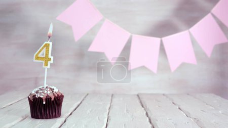 Téléchargez les photos : Birthday number 4. Festive background for a girl or woman with a muffin and candles burning pink in pastel colors with decorations for any holiday, copy space, women's gift boxes, place for text. - en image libre de droit