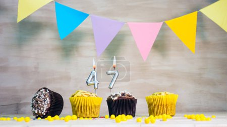 Photo for Birthday background with number 47. Beautiful birthday card with colorful garlands, a muffin with a candle burning copyspace. - Royalty Free Image
