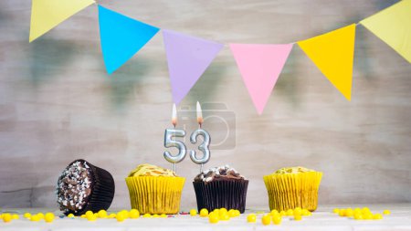 Téléchargez les photos : Birthday background with number 53. Beautiful birthday card with colorful garlands, a muffin with a candle burning copyspace - en image libre de droit