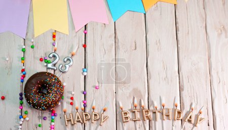 Téléchargez les photos : Birthday with number 23. Donut on the festive table. Happy birthday congratulations top view. Happy birthday card with beautiful decorations on a white board table - en image libre de droit