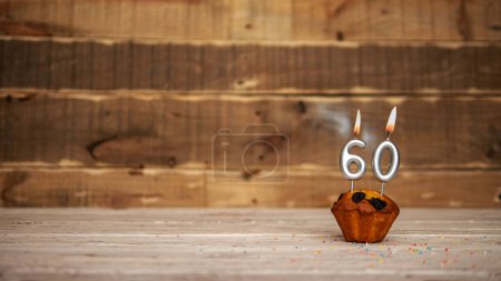Foto de Scenery Festive wooden background happy birthday copy space. Anniversary background with number of burning candles and muffin. Beautiful brown from vintage boards background before a birthday with a number 60. - Imagen libre de derechos