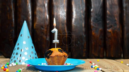 Photo for Beautiful anniversary background happy birthday with a cupcake and a burning candle. Happy birthday anniversary on wooden background with decorations with number 1 - Royalty Free Image