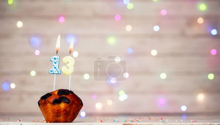 Happy birthday background with muffin and number of candles on light bulbs bokeh background. Greeting card happy birthday copy space with number 13
