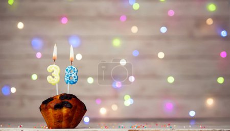 Foto de Happy birthday background with muffin and number of candles on light bulbs bokeh background. Greeting card happy birthday copy space with number 38 - Imagen libre de derechos