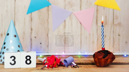 Foto de Festive Happy birthday background with number or digit  38. Postcard with a muffin and burning candles. Festive copy space background. - Imagen libre de derechos