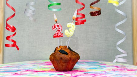 Téléchargez les photos : Happy birthday background with muffin with beautiful decorations with number candles  23. Colorful festive card happy birthday with a number. Anniversary copy space - en image libre de droit