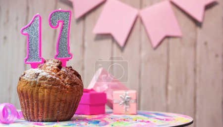 Photo for Festive cake or muffin with a pink candle with a number  17. Happy birthday background with a number for a girl or woman with beautiful decorations. Anniversary party copy space. - Royalty Free Image