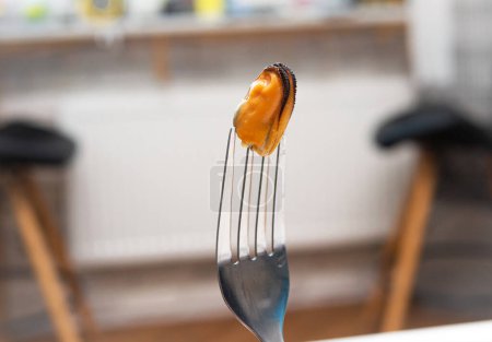 Foto de Fresh mussel on a fork, healthy sea food mussel without shell. A man eats a mussel in a restaurant. Pickled - Imagen libre de derechos