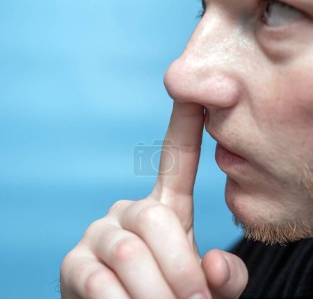 Téléchargez les photos : L'homme se pique le nez. Gros plan d'un homme avec un doigt dans le nez. - en image libre de droit