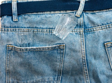 Photo for Empty alcoholic glasses in denim pants. The concept of alcoholism. - Royalty Free Image