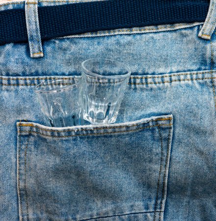 Photo for Top view Empty alcoholic glasses in denim pants. The concept of alcoholism. - Royalty Free Image