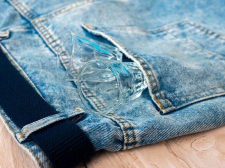 Photo for Top view Empty alcoholic glasses in denim pants. The concept of alcoholism. Glasses for cognac. - Royalty Free Image