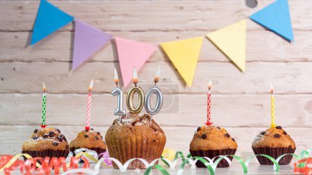 Festlicher Geburtstagskuchen mit Kerzen. Geburtstagshintergrund mit Zahlen 100. Jubiläums-Karten auf Holzgrund.