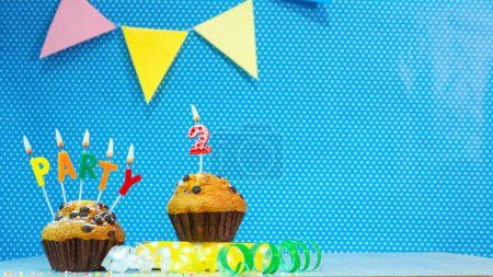 Festlicher Muffinkuchen mit Kerzen zum Geburtstag. Geburtstag Hintergrund mit Zahlen 2. Jubiläums-Karte auf blauem Tupfen-Hintergrund, Kopierraum