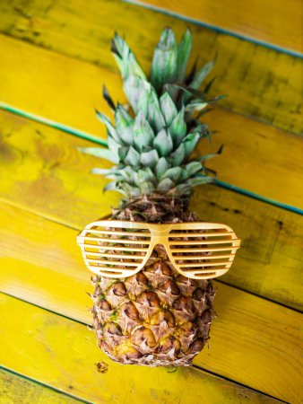 Foto de Piña en gafas de sol sobre un fondo creativo de madera pintado de amarillo. Copia espacio de fondo creativo con carácter de fruta de piña. vista superior - Imagen libre de derechos
