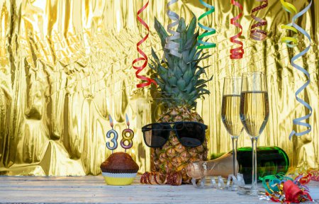 Cheerful pineapple in glasses festive happy birthday character with number  38. Beautiful background for congratulations copy space on a golden background with glasses of champagne. Anniversary congratulations with the number of candles burning with 