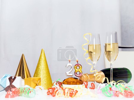 Foto de Fecha de nacimiento 28. Fondo festivo con una botella de champán. Champán festivo en copas con cajas de regalo, tarjeta de aniversario, decoraciones de feliz cumpleaños en colores blancos - Imagen libre de derechos