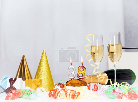 Foto de Fecha de nacimiento 38. Fondo festivo con una botella de champán. Champán festivo en copas con cajas de regalo, tarjeta de aniversario, decoraciones de feliz cumpleaños en colores blancos - Imagen libre de derechos