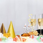 Date of Birth  75. Festive background with a bottle of champagne. Festive Champagne in glasses with gift boxes, anniversary card, happy birthday decorations in white colors