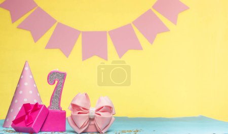 Date of birth for a girl  7. Copy space. Birthday in pink shades with a yellow background. Decorations with numbered candles and a gift box. Anniversary card for a woman